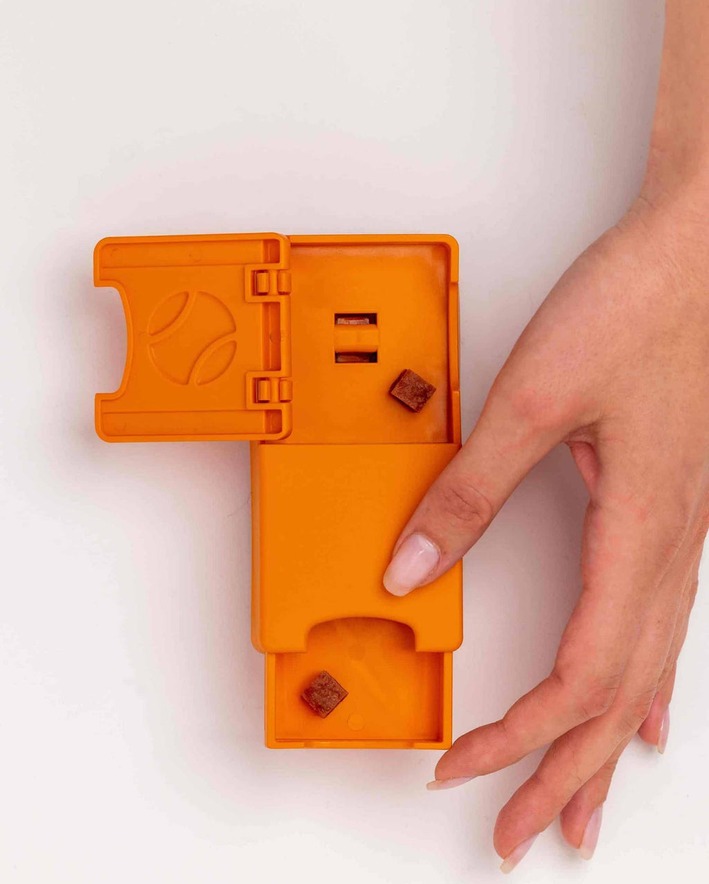 Main faisant glisser le tiroir orange contenant une friandise