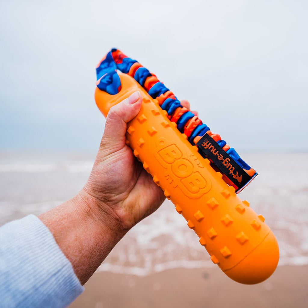 Main tenant le bâton orange sur une plage
