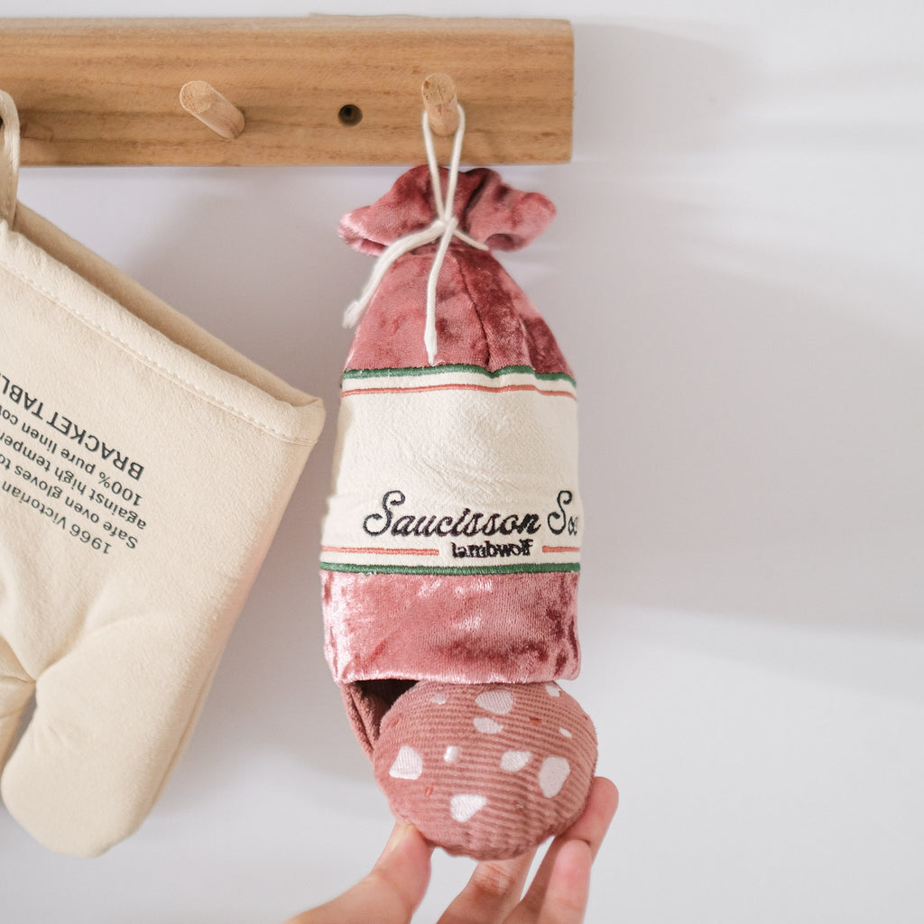 Saucisson suspendu à une patère à côté d'un gant de cuisine