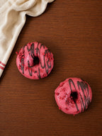Deux donuts roses posés sur une table en bois