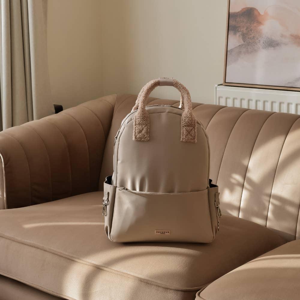 Sac beige posé sur un canapé en cuir