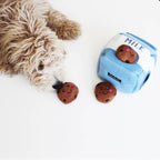Chien frisé qui fouille la brique de lait et sort les cookies