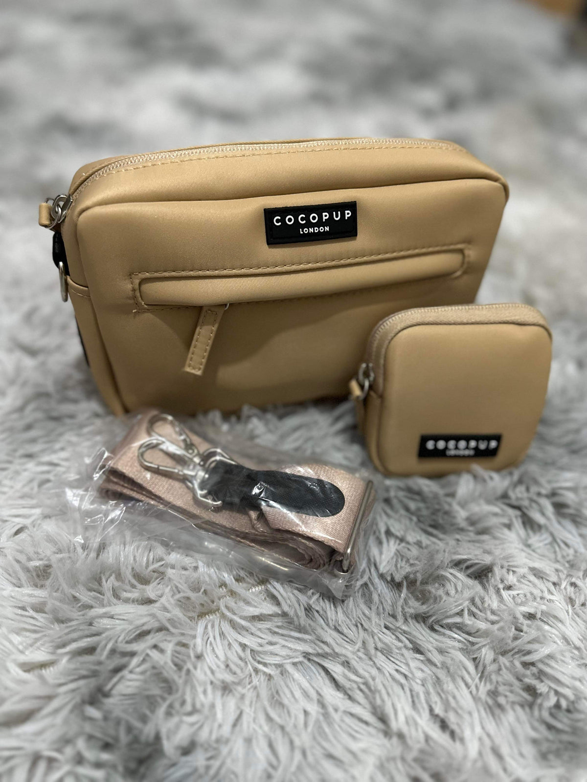 Sac camel et pochette assortie posés sur une fourrure